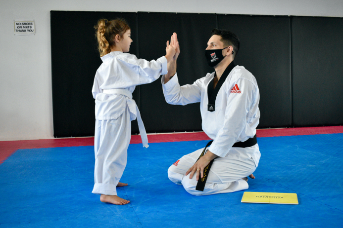 Marco, the owner of Black Rock Martial helps a child martial arts student with their punching form.