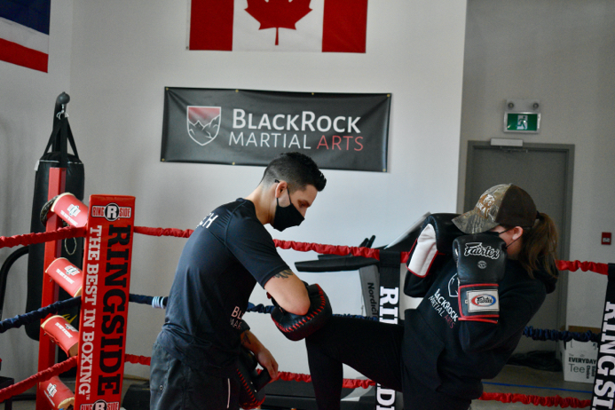 Marco of Black Rock Martial Arts takes kicks from a martial arts student.