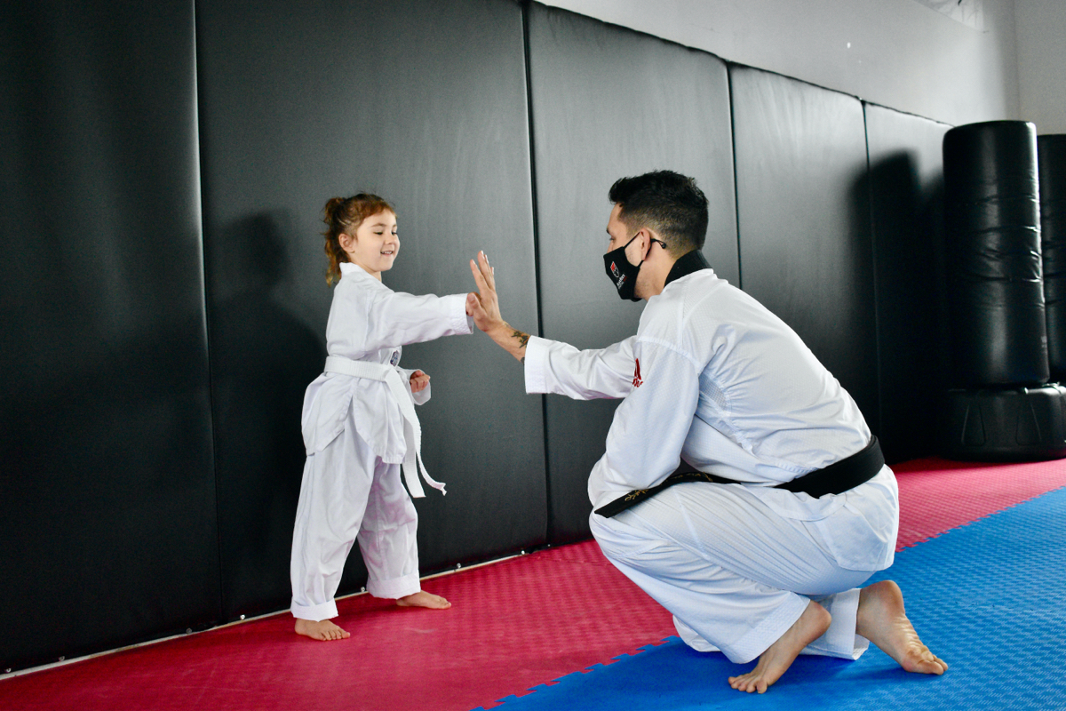 Marco, the owner of Black Rock Martial Arts, high fives a young girl martial arts student.